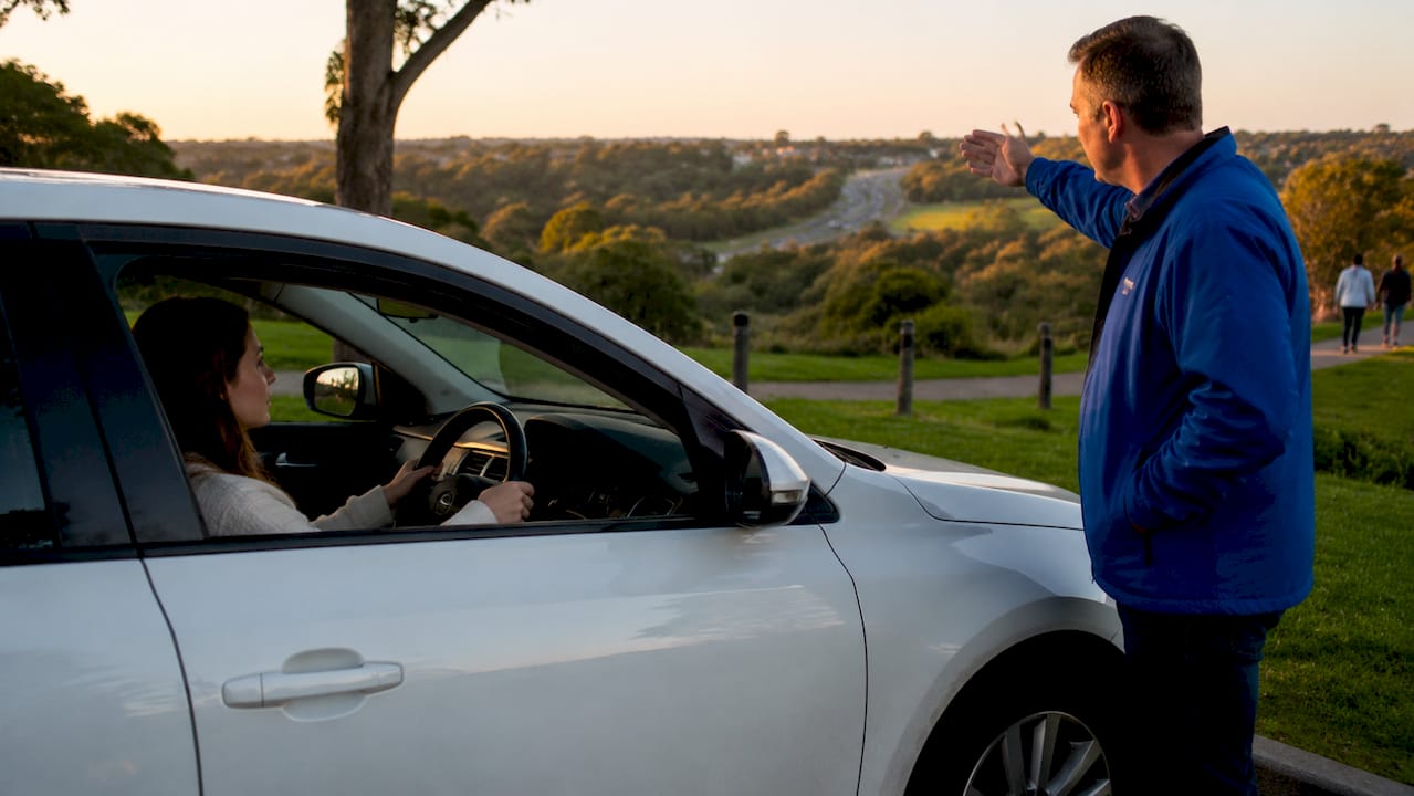Driving instructor teaching learner near roundabout outdoors